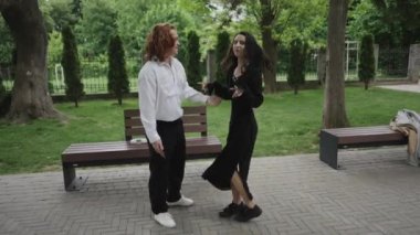 Yürek ısıtan bir video parkta bir erkek ve bir kadın kucaklaşırken, iki kadın neşeyle dans ediyor, ilişkileri kutluyorlar.