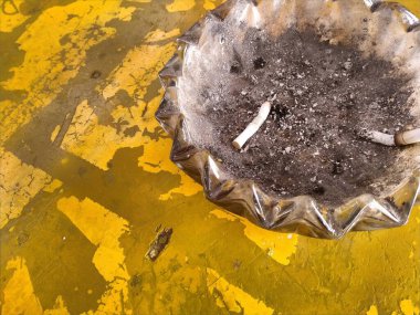 dirty yellow metal plate table with cigarette ashtray