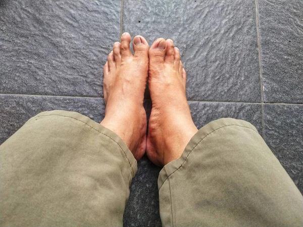 Man\'s bare feet on floor great for any use.