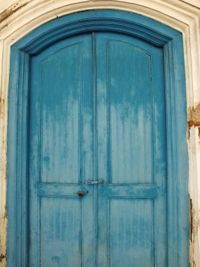 Eski ve antika mavi ahşap java kapısı. Etrafında çatlak eski bir duvar var.