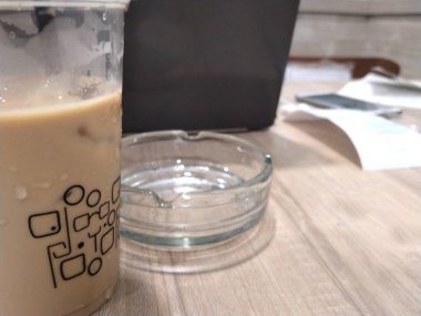 Evden işi kapatıyoruz. Bilgisayarlı ofis masası, kağıt notlar, kahve fincanı, sigara küllüğü.