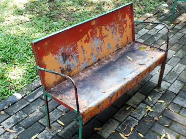 Bahçede paslı demir sandalye ve üzerine kuru yapraklar dökülüyor..