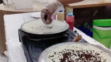 Şefin ellerinin krep yaparken yakın plan fotoğrafı. Yavaş çekim sahnesi kızartma tavasının önünde
