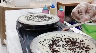 Şefin ellerinin krep yaparken yakın plan fotoğrafı. Yavaş çekim sahnesi kızartma tavasının önünde