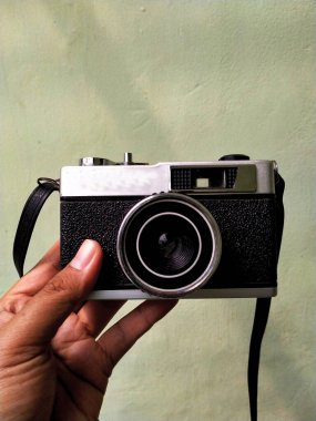 Parlak bir arka planda izole edilmiş eski bir kamera donanımını tutuyorum. Retro fotoğraf klasiği. Nostaljik tatil tarihi anı