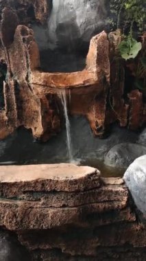 Yapay taşlı küçük bir gölette yapay bir şelale. Terasta dinleniyor.