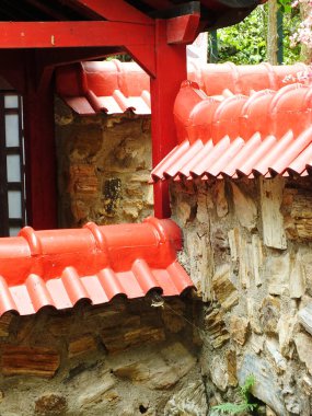 Arka planda taş duvar olan kırmızı çatı. Çatı kırmızı ve fayans deseni var. Açık hava klasik teras tasarımı Japon tarzı.