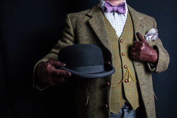 Portrait of Man in Tweed Suit Holding Bowler Hat on Black Background. Vintage Style and Retro Fashion of English Gentleman.