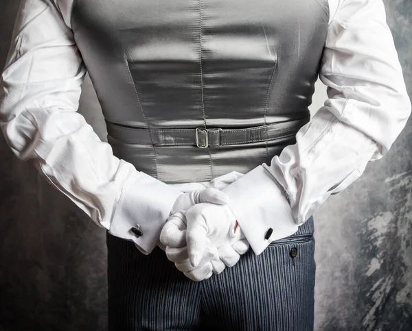 Closeup of Butler or Waiter in White Gloves Standing With Hands Behind Back. Concept of Service Industry and Elegant Hospitality.