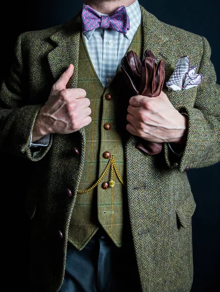 Portrait of British Gentleman in Tweed Suit Holding Leather Gloves and Standing Proudly on Black Background. Vintage Style and Retro Fashion.
