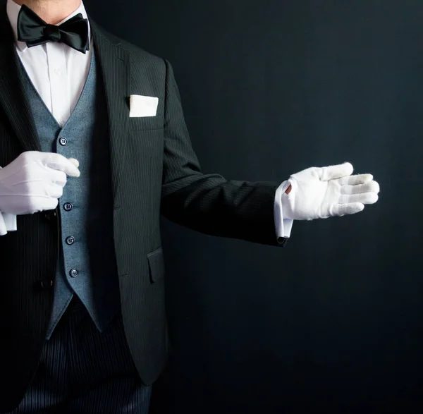 Portrait of Butler With Welcoming Gesture in Formal Suit and White Gloves. Service Industry and Professional Courtesy.