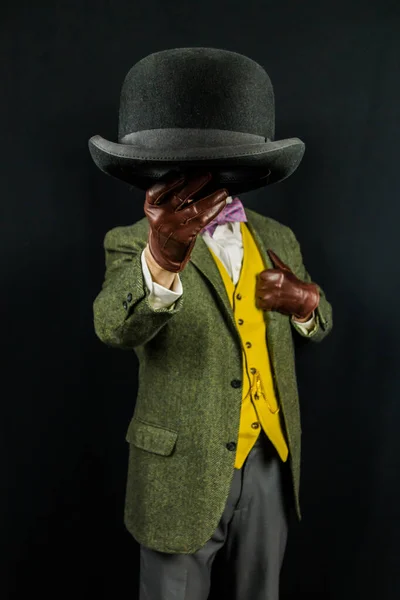 Portrait of Successful Man in Tweed Suit and Leather Gloves Holding Bowler Hat on Black Background. Retro Style and Vintage Fashion of Classic British Gentleman