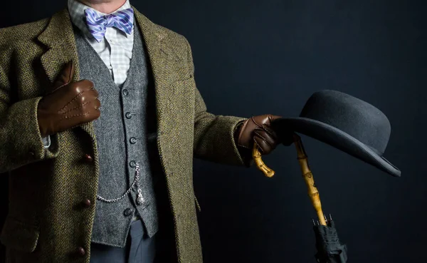 Portrait of Elegant English Gentleman in Tweed Suit Holding Umbrella and Bowler Hat. Vintage Style and Retro Fashion of British Gentleman.