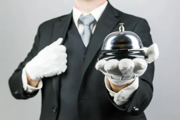 Portrait of Butler or Hotel Concierge Holding Silver Bell. At Your Service Concept. Professional Hospitality.