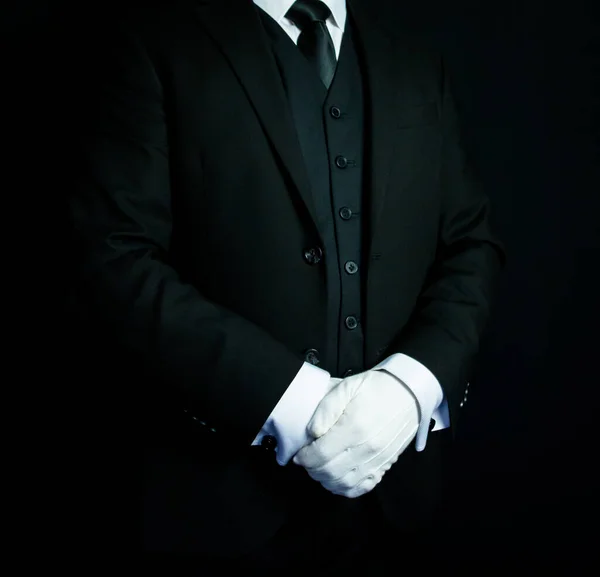 Portrait of Butler or Concierge in Black Formal Suit and White Gloves Standing at Elegant Attention. Service Industry and Professional Hospitality.
