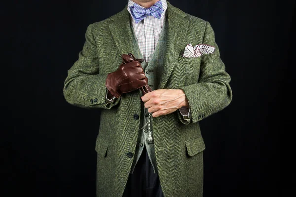 Gentleman in Tweed Suit Holding Leather Gloves on Black Background. Concept of Classic and Eccentric British Gentleman