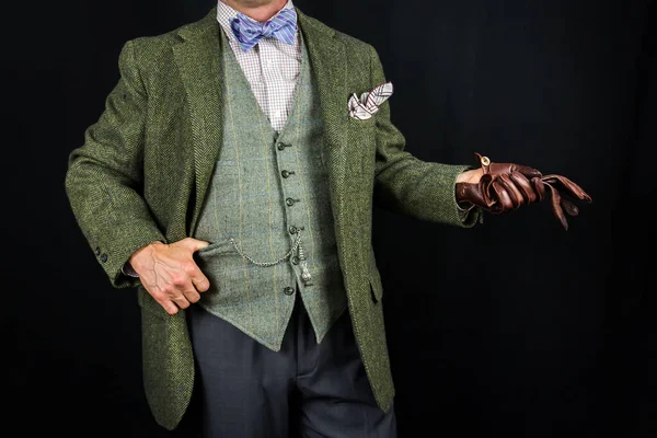 Elegant Man in Tweed Suit Holding Leather Gloves on Black Background. Concept of Classic and Eccentric British Gentleman Stereotype