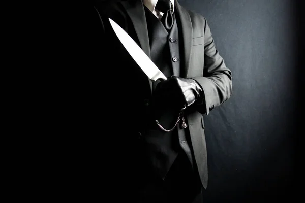 Portrait of Man in Dark Suit and Leather Gloves Holding Sharp Knife on Black Background. Stylish Gentleman Who Will Cut You. Mafia Hitman