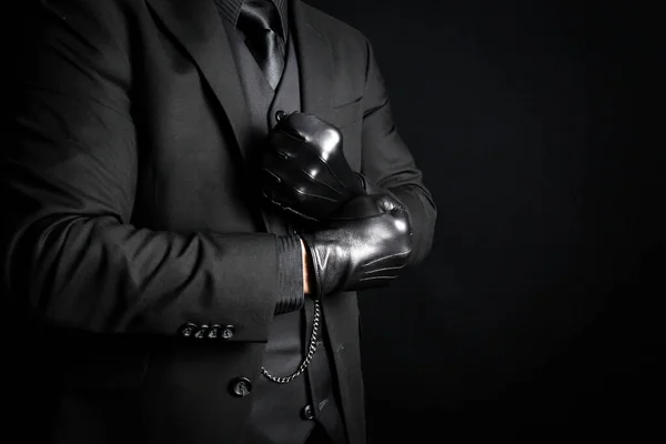 Mafia Gangster in Dark Suit Pulling on Black Leather Gloves. Threat of Danger and Physical Violence.