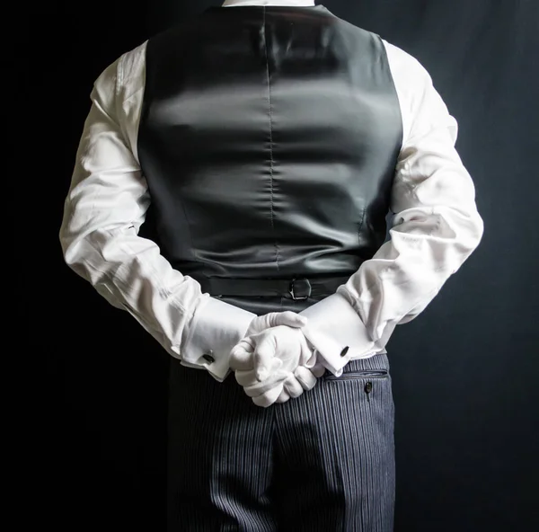 Black and White Portrait of Butler or Waiter in Vest or Waistcoat and White Gloves Holding Hands Behind Back. Service Industry and Professional Hospitality.