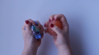 Womens hands crumple and crush rubber silicone fruit and dolphin close-up top view. Board game for the development of motor skills. Trendy toy fidget. Silicone soft stretchable toys. Antistress toy