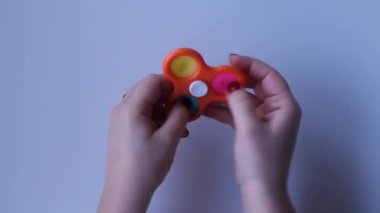 Women hands crumple and play with spinner Pop It close-up top view. Board game for the development of motor skills. Educational concept. Popit gamer. Antistress toy. Pressing bubbles. Spinner rotation