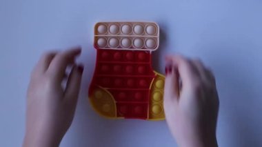 Women hands crumple and play with large Pop It Christmas sock close-up top view. Board game for the development of motor skills. Christmas concept. Popit gamer. Antistress toy.