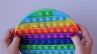 Women hands crumple and play with large round Pop It close-up top view. Board game for the development of motor skills. Trendy toy Big Pop It fidget. Popit gamer. New antistress toy. Pressing bubbles
