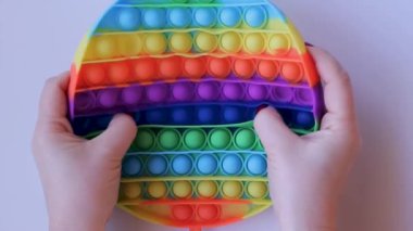 Womens hands with a beautiful manicure gently and sexily crumple a rubber soothing toy. Pop It close-up top view. Board game for the development of motor skills. Popit gamer. Antistress toy