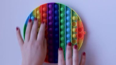 Women hands crumple and play with large round Pop It close-up top view. Board game for the development of motor skills. Trendy toy Big Pop It fidget. Popit gamer. New antistress toy. Pressing bubbles.