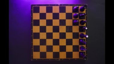 The appearance of chess pieces on the old playing field before the start of the game. Timelapse top view chess game. Wooden chessboard on a dark background with chess pieces. Stop motion 4k footage