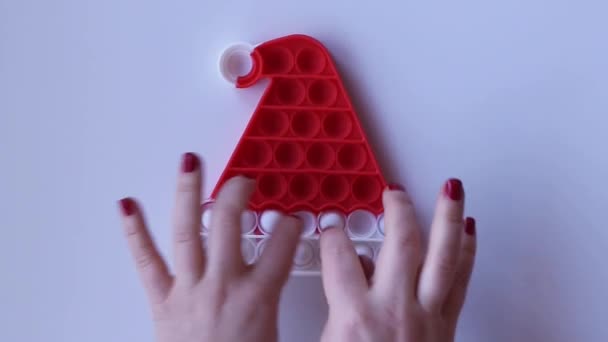 女人的手揉皱了 玩着大大的圣诞礼帽特写 棋盘游戏开发运动技能 圣诞节的概念流行游戏玩家 新的抗压玩具 挤压气泡 — 图库视频影像