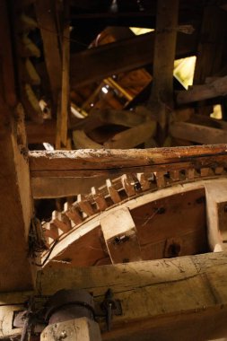 An ancient clockwork mechanism made of wood close-up, a clock tower from the inside. Huge wooden clock gears and wheels. An ancient mechanism made of wood, covered with cobwebs. Outdated technologies.