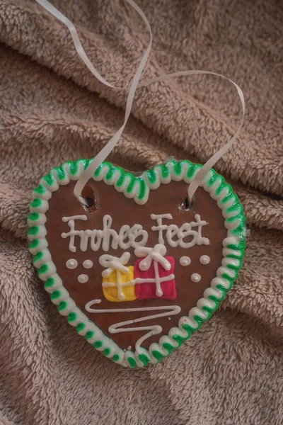 Green gingerbread with ribbon lies on a brown fabric background close-up from above. Christmas food. Festive decoration. Handmade gingerbread. Selective focus.