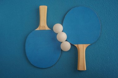 Two blue table tennis or ping pong rackets lie on a blue background with a close-up view from above. Game for leisure. Sport equipment. International competition. Table tennis. Healthy lifestyle