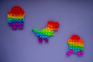 Trendy pop it and simpl dimple toys in form of dinosaur, and a character among us on a Very Peri background color. Top view Flat lay