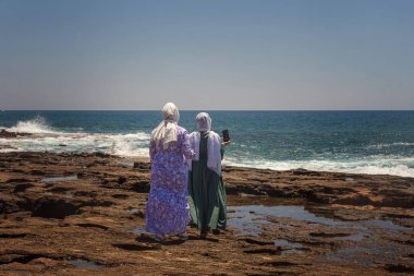 Young Turkish women, tourist travelers makes a selfie on a mobile phone against the background of the sea. Lifestyle. Stream blogger, influencer, Travel bloger. Selective focus. Selective focus.