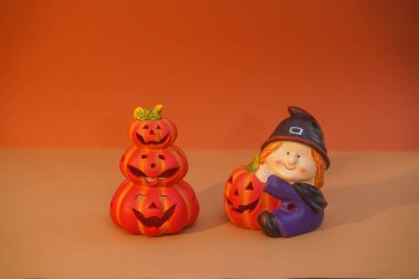Cheerful fairy-tale figures made of clay and paper. Friendly little man makes fun pumpkins for Halloween. DIY with your own hands. Home decor. Orange background. Selective focus