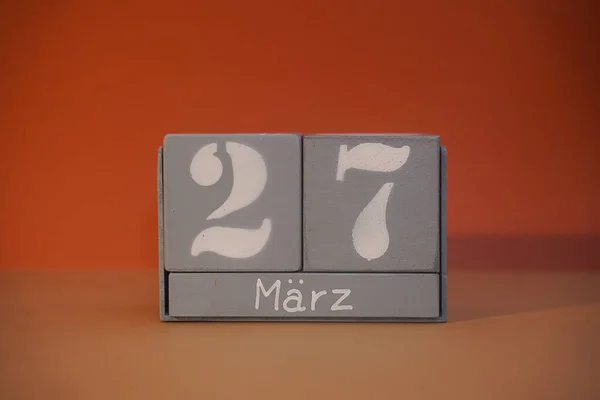 27 Marz on wooden grey cubes. Calendar cube date 27 March. Concept of date. Copy space for text or event. Educational cubes. Wood blocks in box with german date, day and month. Selective focus