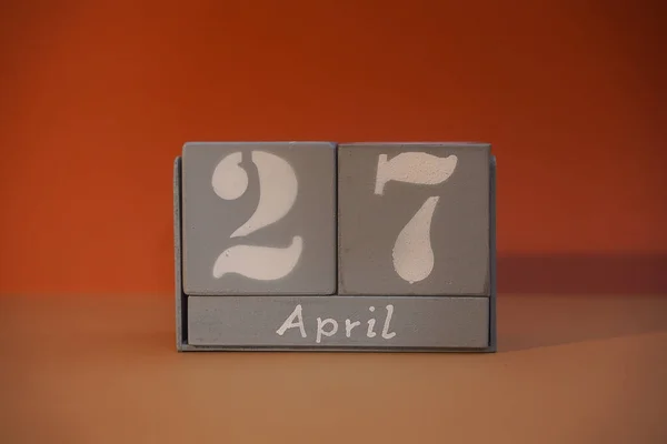 27 April on wooden grey cubes. Calendar cube date 27 April. Concept of date. Copy space for text or event. Educational cubes. Wood blocks in box with date, day and month. Selective focus