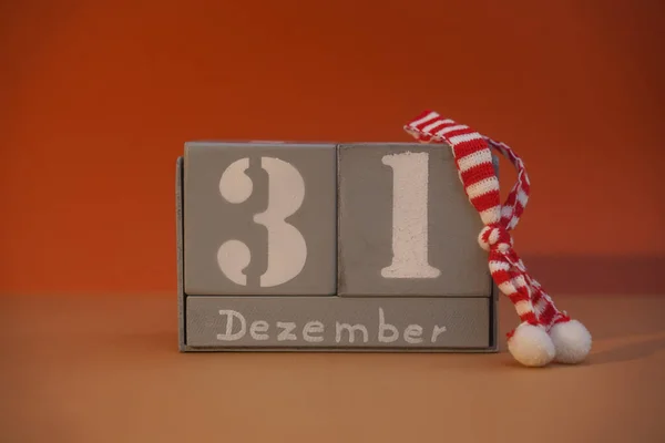 31 Dezember on wooden grey cubes with Christmas striped scarf. Calendar cube date 31 December. Concept of date. Copy space for text. Wood blocks in box with german date, day and month. Selective focus