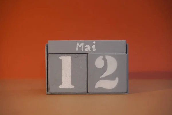 12 Mai on wooden grey cubes. Calendar cube date 12 May. Concept of date. Copy space for text or event. Educational cubes. Wood blocks in box with german date, day and month. Selective focus