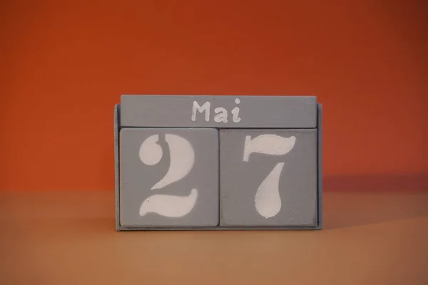 27 Mai on wooden grey cubes. Calendar cube date 27 May. Concept of date. Copy space for text or event. Educational cubes. Wood blocks in box with german date, day and month. Selective focus