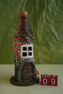 Decorative fairy-tale vintage house tower of bottle and improvised materials with red wooden cubes number 09. DIY. Handmade decor in grunge style. Date time concept. Blurred background