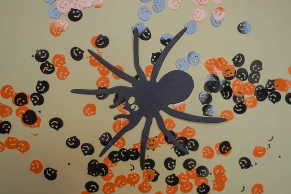 Big Black Flat Paper Spider. Halloween holiday frame with party decorations of pumpkins, bats, ghosts, spiders on grey background top view. Happy halloween card in flat lay style.