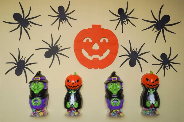 Cute characters in monster costume. Scary Halloween figurines stand on a light background in close-up, behind hangs terrible pumpkin. Halloween concept. Holiday decorations, toys and entertainment.
