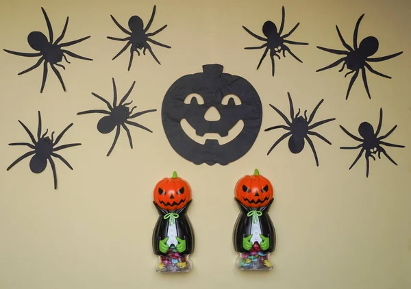 Cute characters in monster costume. Scary Halloween figurines stand on a light background close-up, behind hangs terrible black pumpkin and spiders. Halloween concept. Holiday decorations, toys.