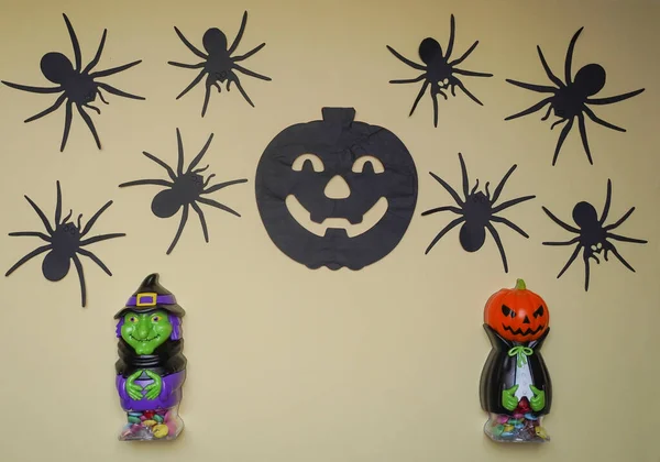 Cute characters in monster costume. Scary Halloween figurines stand on a light background close-up, behind hangs terrible black pumpkin and spiders. Halloween concept. Holiday decorations