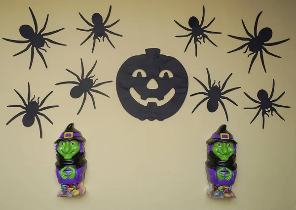 Cute toys in monster costume. Scary Halloween figurines stand on a light background close-up, behind hangs terrible black pumpkin and spiders. Halloween concept. Holiday decorations