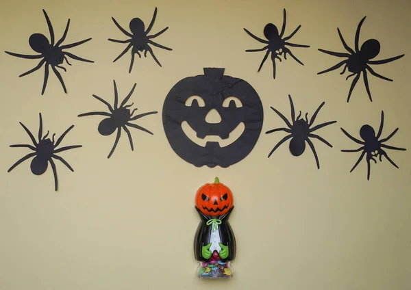 Cute toys in monster costume. Scary Halloween figurines stand on a light background close-up, behind hangs terrible black pumpkin and spiders. Halloween concept.